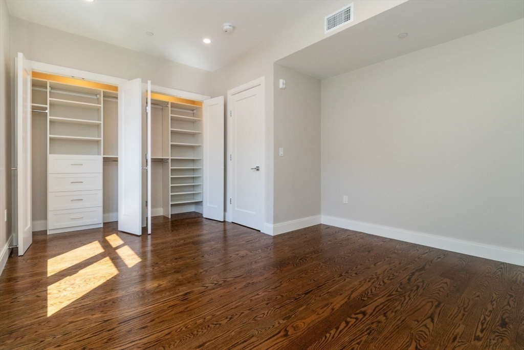 15 Tanglewood Road, Unit A Boston, MA 02126 - Photo 16 of 28 an empty room with wooden floor closet and windows