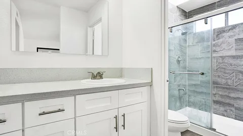 a bathroom with a granite countertop sink a toilet and shower