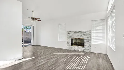 an empty room with wooden floor fireplace and windows