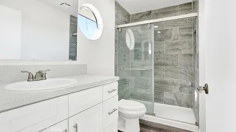 a bathroom with a granite countertop sink a toilet and a mirror