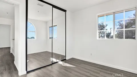 a view of an empty room with wooden floor and a mirror