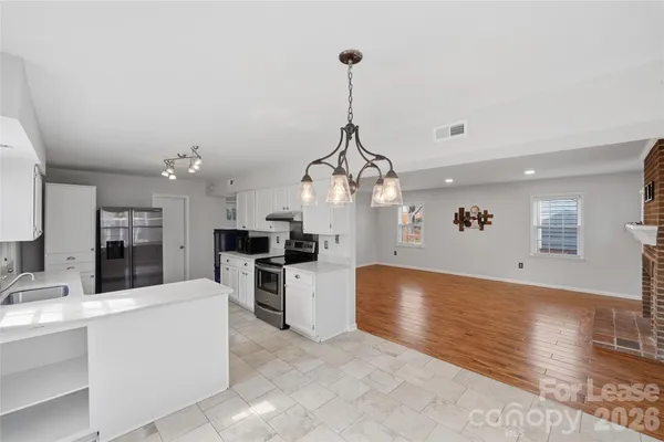 a large white kitchen with a stove a refrigerator and a sink