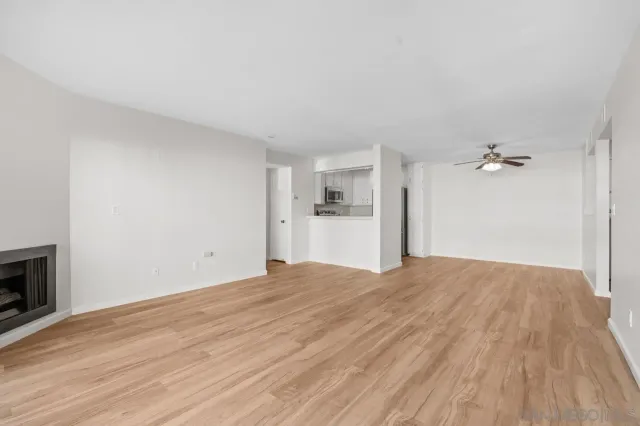 a view of empty room with wooden floor and ceiling fan