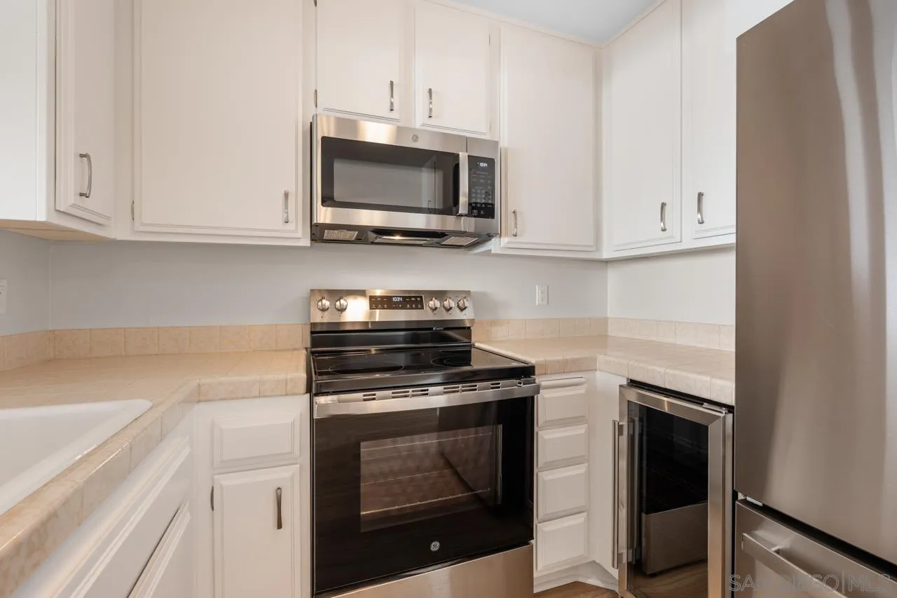 6747 Friars Road, Unit 110 San Diego, CA 92108 - Photo 9 of 24 a kitchen with white cabinets and stainless steel appliances