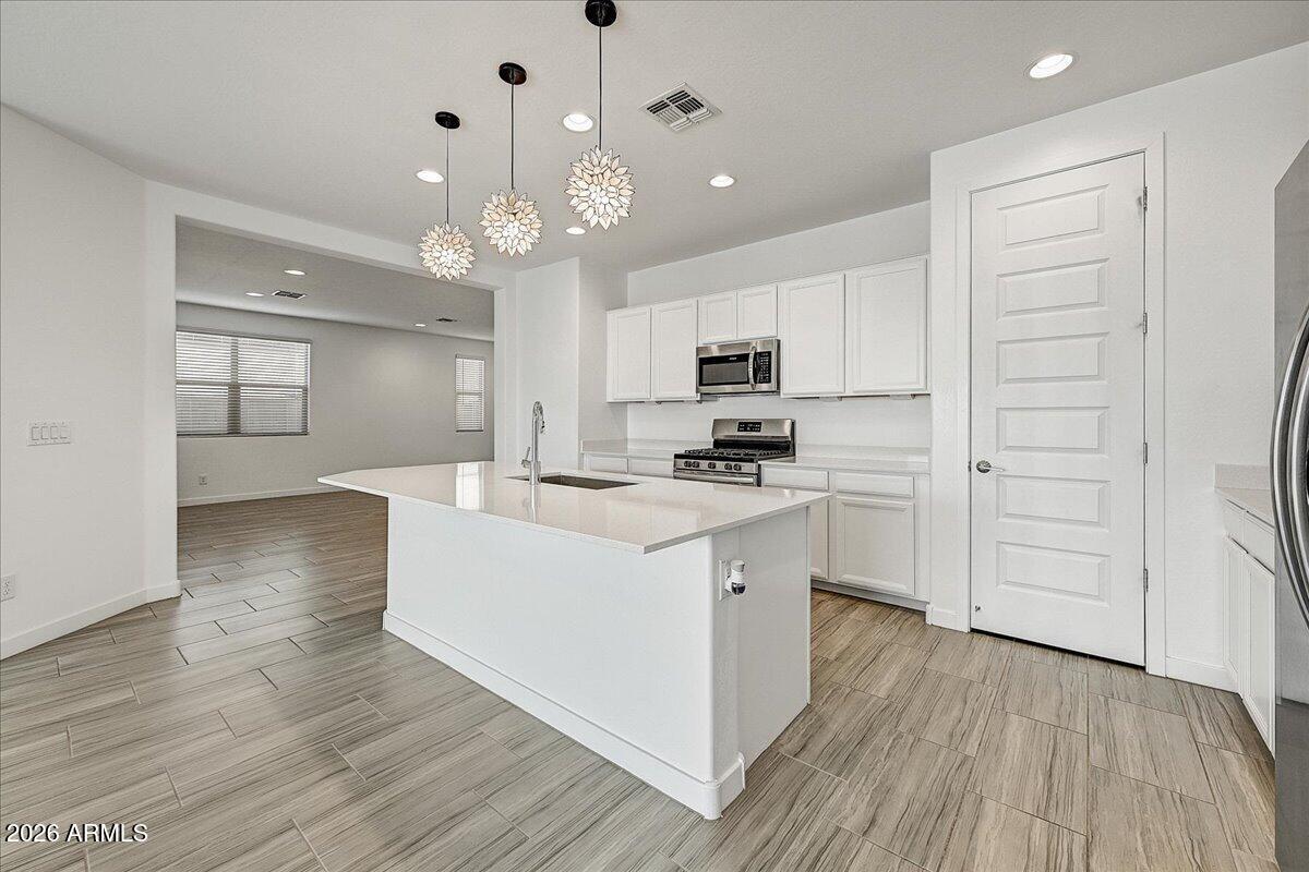 1642 West Monte Way Phoenix, AZ 85041 - Photo 5 of 20 a large kitchen with cabinets wooden floor and stainless steel appliances