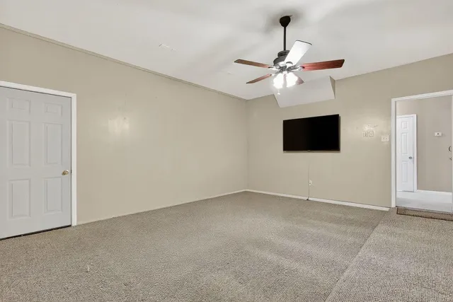 a view of an empty room with a ceiling fan window and a ceiling fan