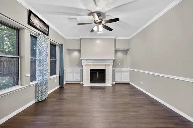 a view of a livingroom with a fireplace a ceiling fan and windows