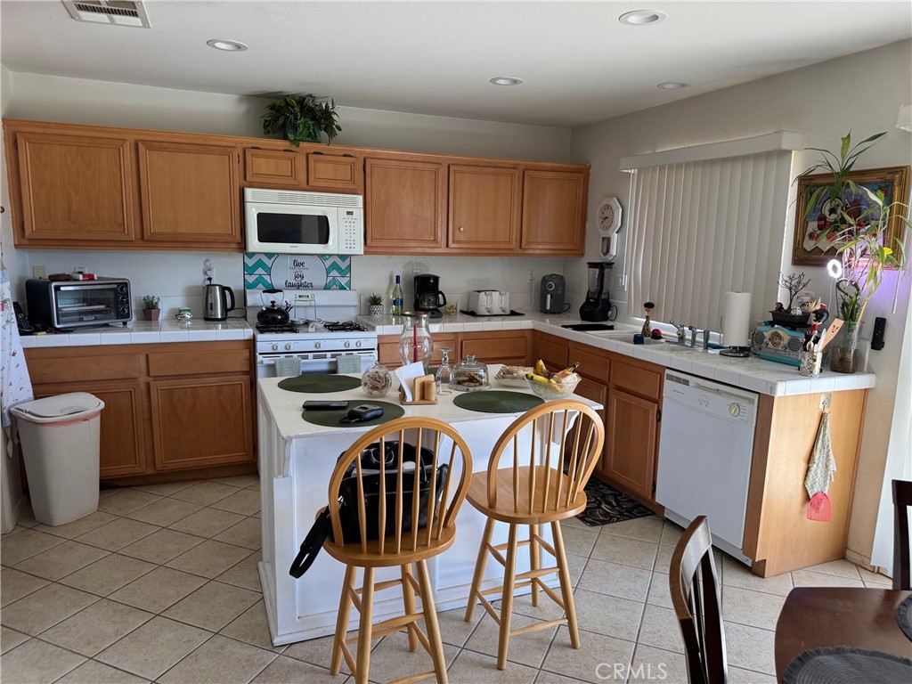 1338 Smoke Tree Lane Beaumont, CA 92223 - Photo 13 of 15 a kitchen with stainless steel appliances a table chairs sink and cabinets