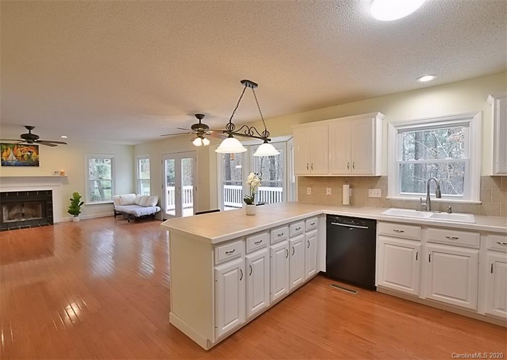 11068 Deep Cove Drive Tega Cay, SC 29708 - Photo 17 of 34 a large kitchen with a sink dishwasher a stove and white cabinets with wooden floor
