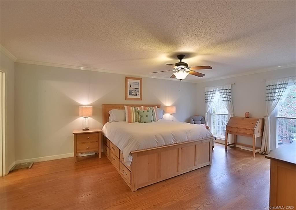 11068 Deep Cove Drive Tega Cay, SC 29708 - Photo 19 of 34 a spacious bedroom with a bed and dresser with wooden floor