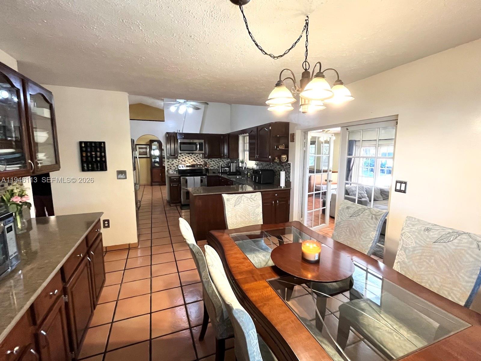 16200 Southwest 284th Street Homestead, FL 33033 - Photo 8 of 23 a kitchen with stainless steel appliances granite countertop a stove top oven a sink a dining table and chairs with wooden floor