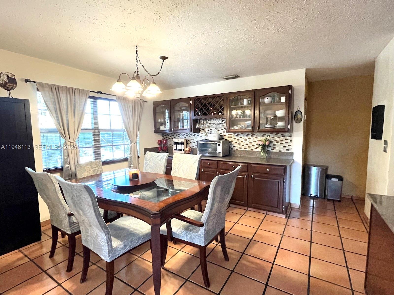 16200 Southwest 284th Street Homestead, FL 33033 - Photo 9 of 23 a dining room with furniture a chandelier and window