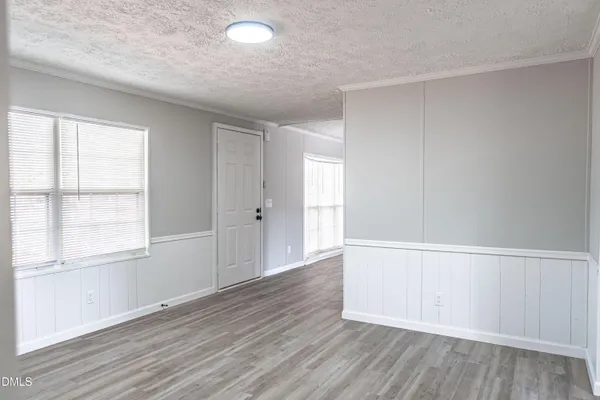 an empty room with wooden floor and windows