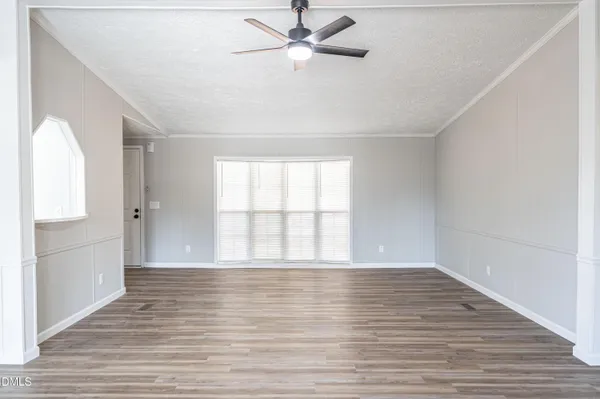 a view of an empty room with window and wooden floor