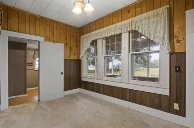 en empty room with windows and chandelier fan