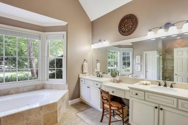 a bathroom with a tub a sink and a large window