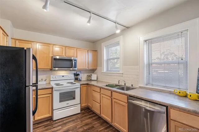 a kitchen with a sink a stove a refrigerator cabinets and a window