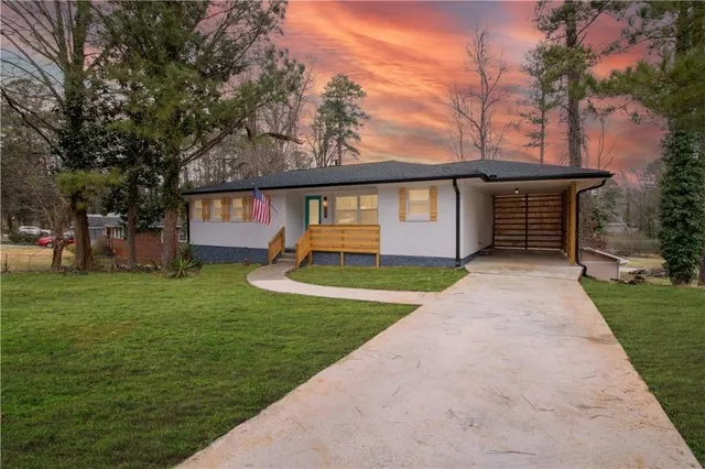 a front view of a house with a garden and trees