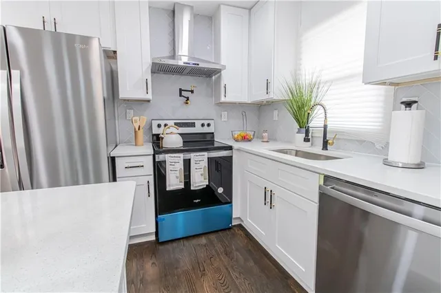 a kitchen with stainless steel appliances a refrigerator sink and white cabinets