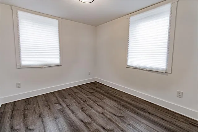 an empty room with wooden floor closet and windows