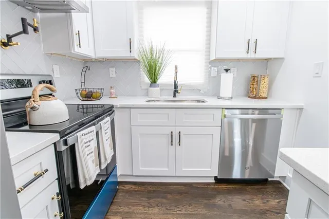 a kitchen with white cabinets and sink