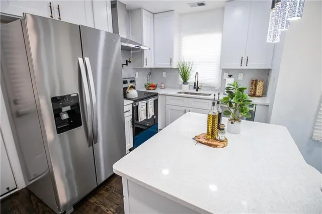 a kitchen with stainless steel appliances a refrigerator a sink a stove a chimney a refrigerator and a window