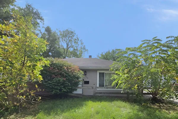 a view of house with garden space and trees in the background