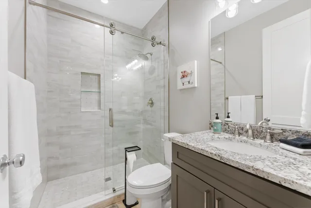 a bathroom with a granite countertop sink a toilet and shower