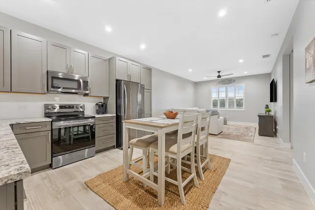 a kitchen with stainless steel appliances kitchen island granite countertop a stove a refrigerator a sink a table and chairs