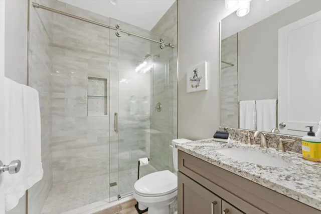 a bathroom with a granite countertop sink toilet mirror and shower