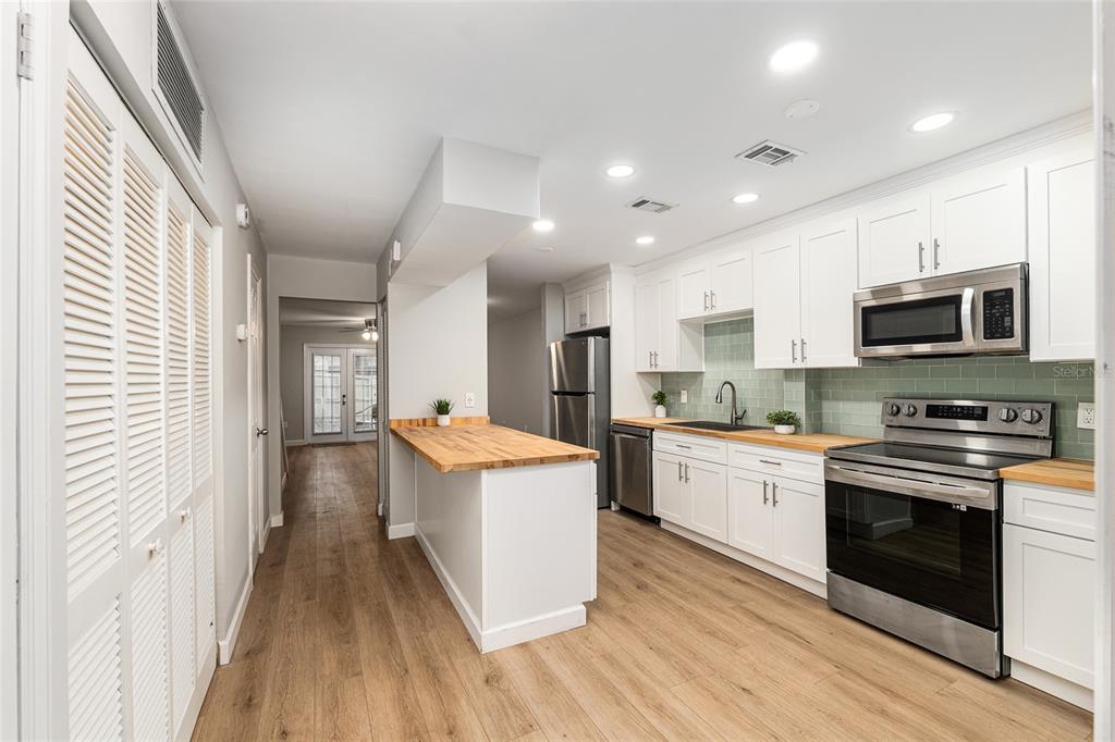 5240 Southwest 92nd Court Gainesville, FL 32608 - Photo 13 of 58 a kitchen with stainless steel appliances granite countertop wooden floors and white cabinets