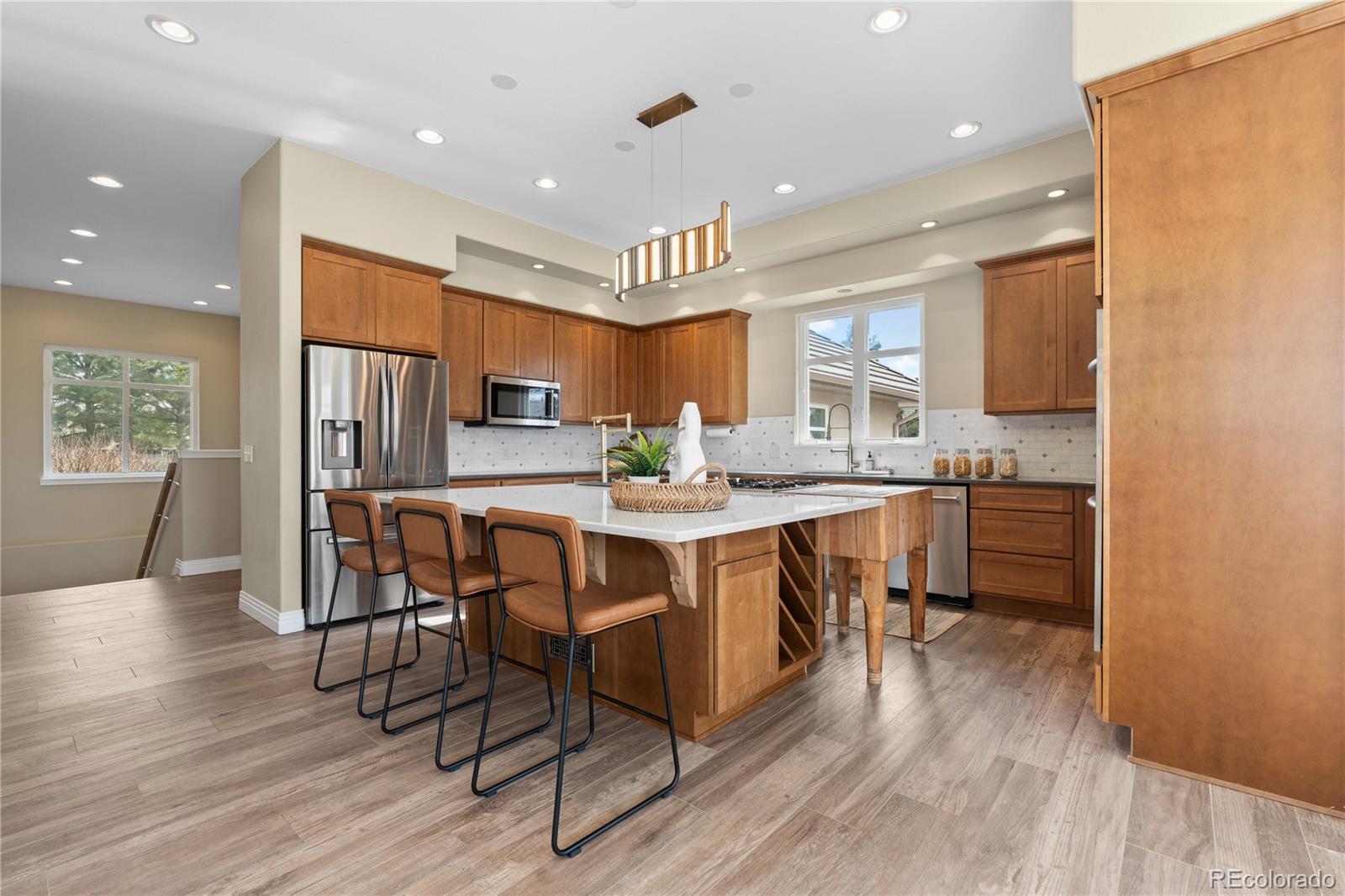 6329 Diamond Ridge Parkway Castle Rock, CO 80108 - Photo 8 of 47 a kitchen with stainless steel appliances kitchen island granite countertop a refrigerator a stove a microwave oven a dining table and chairs with wooden floor