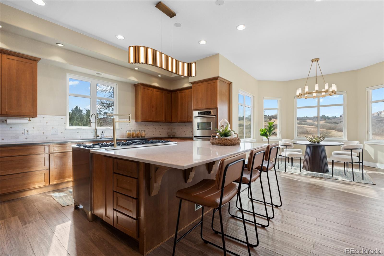 6329 Diamond Ridge Parkway Castle Rock, CO 80108 - Photo 9 of 47 a kitchen with granite countertop a stove a sink a dining table and chairs with wooden floor