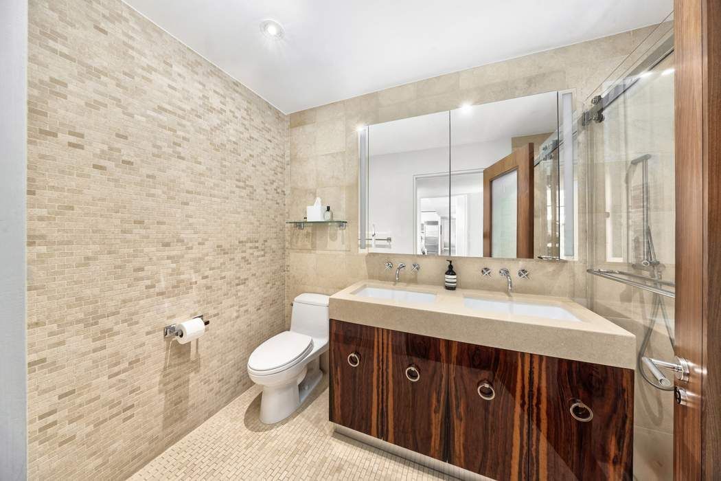 433 East 74th Street, Unit 4A Manhattan, NY 10021 - Photo 21 of 34 a spacious bathroom with a double vanity sink toilet and a mirror