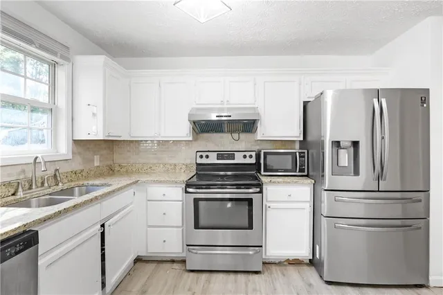 a kitchen with cabinets stainless steel appliances and window
