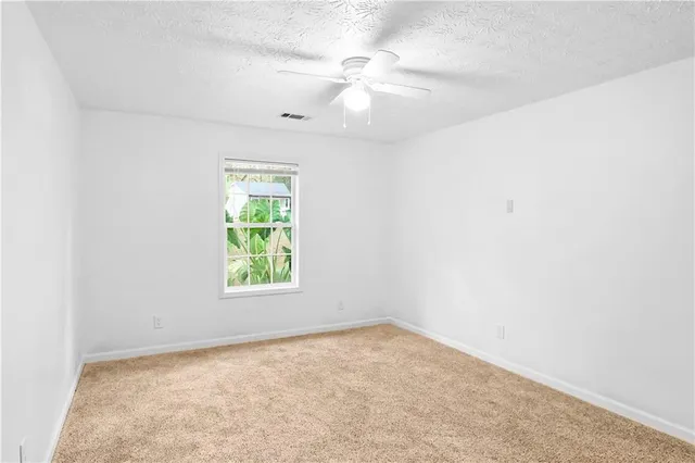 an empty room with windows and fan