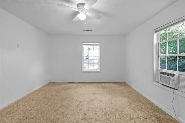 en empty room with windows and chandelier fan