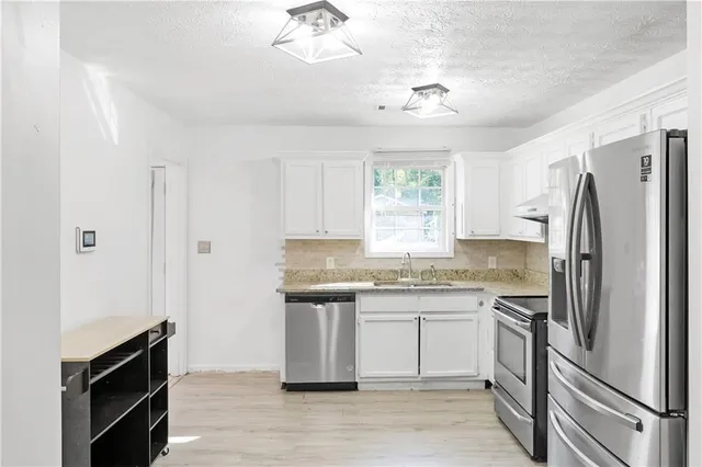 a kitchen with stainless steel appliances granite countertop a refrigerator and a sink