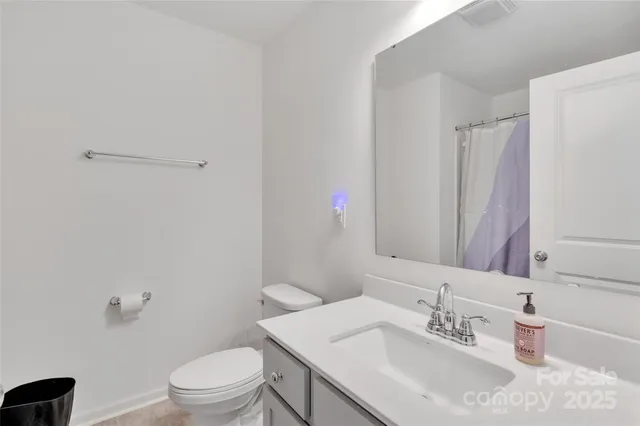 a bedroom with a bed a chair and three windows