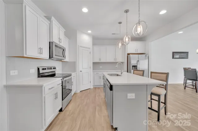 a kitchen with a stove a sink a refrigerator and chairs