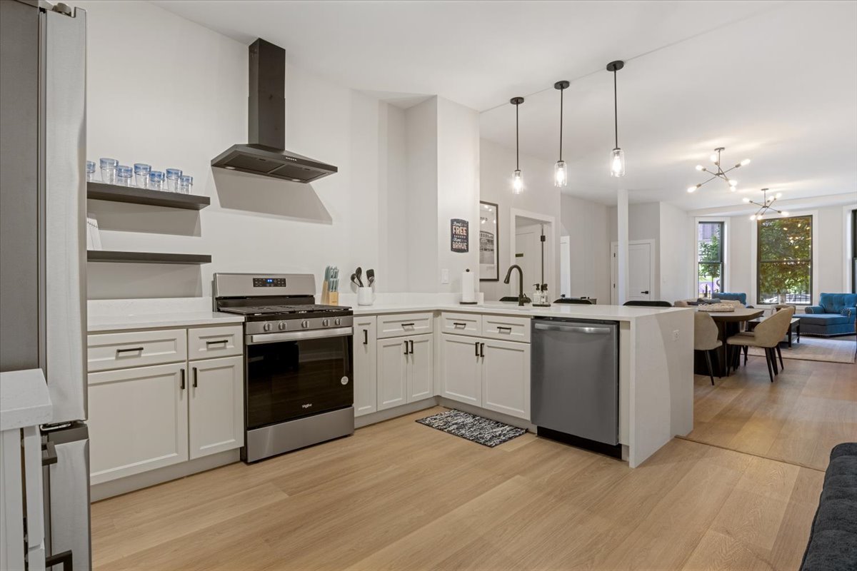 1110 West Addison Street Chicago, IL 60613 - Photo 14 of 49 a kitchen with a sink dishwasher and white cabinets with wooden floor