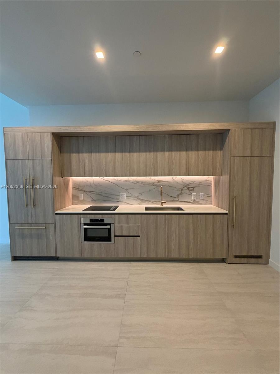 77 Southeast 5th Street, Unit 1208 Miami, FL 33131 - Photo 5 of 32 a kitchen with granite countertop a stove and a refrigerator