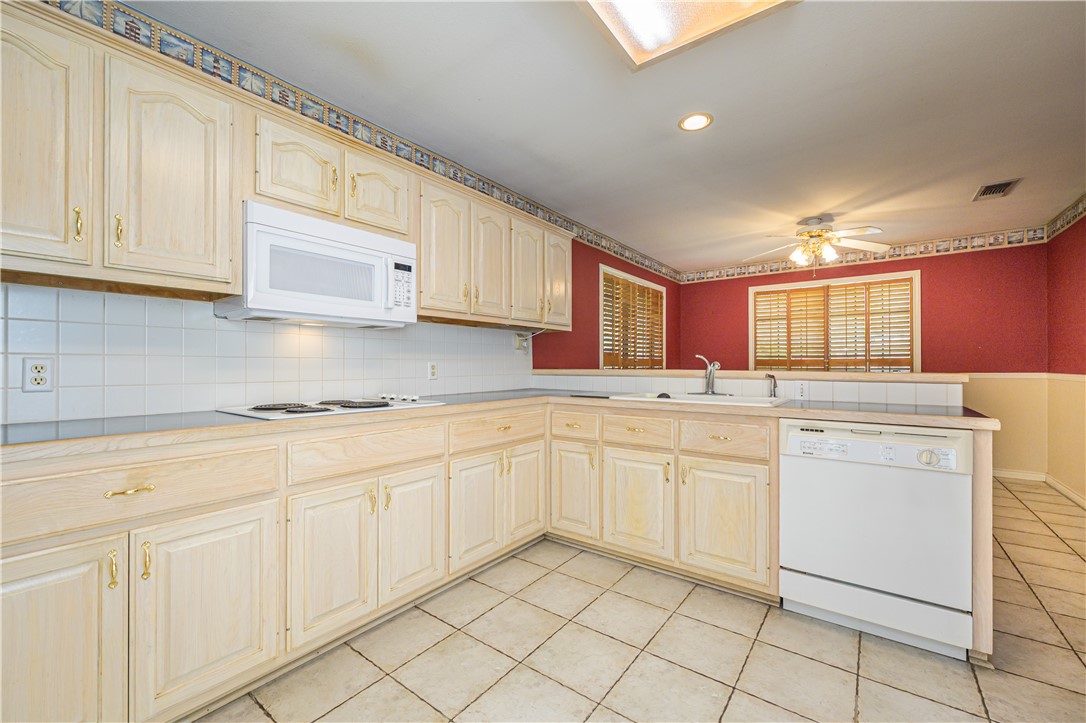 10416 7th Street Pettus, TX 78146 - Photo 35 of 40 a kitchen with granite countertop white cabinets white appliances with a sink and dishwasher