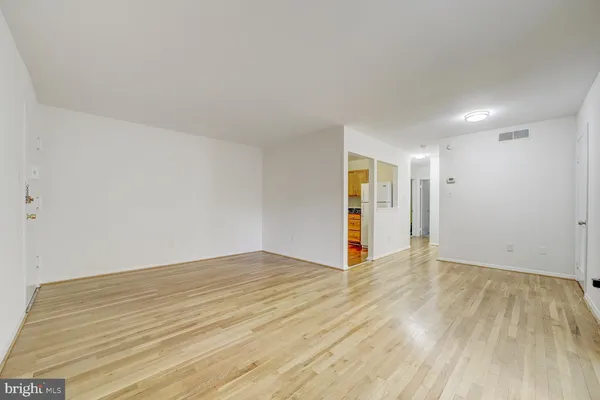 a view of an empty room with wooden floor and closet