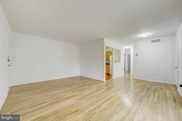 a view of an empty room with wooden floor and closet