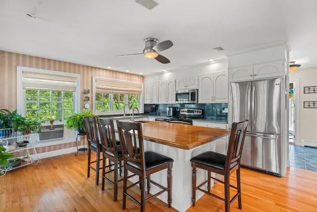 a kitchen with stainless steel appliances granite countertop dining table chairs and wooden floor