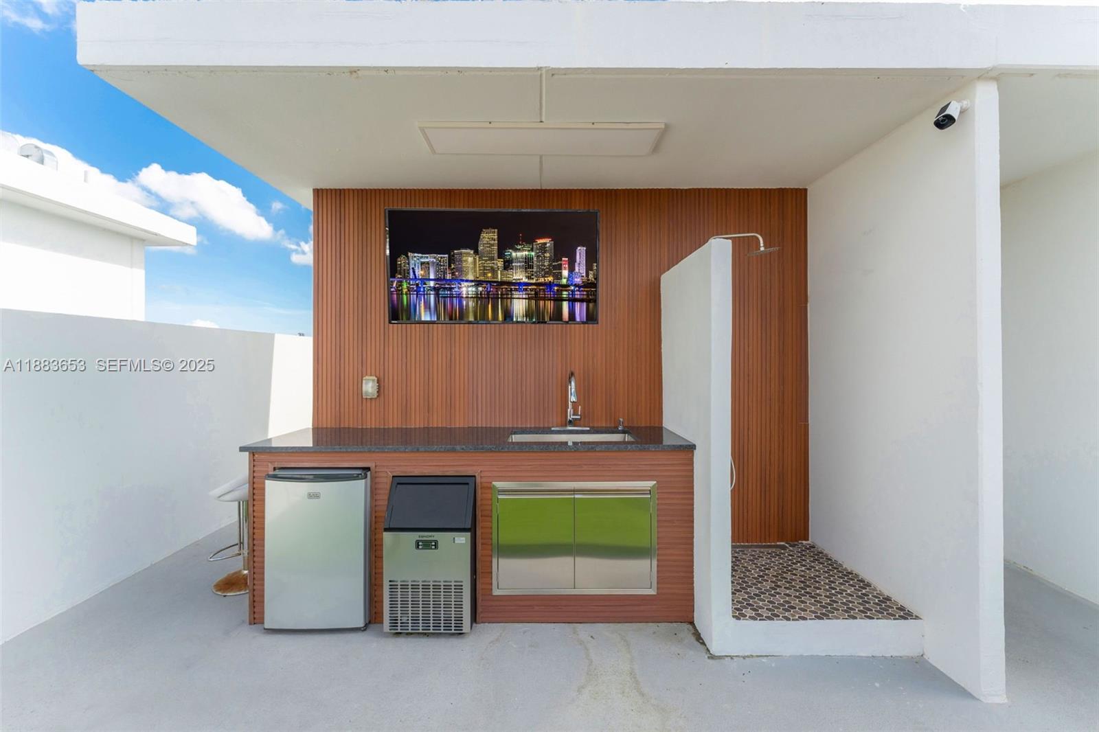 26144 Southwest 146th Court Homestead, FL 33032 - Photo 26 of 35 Modern outdoor bar with sink, fridge, and wall-mounted TV.