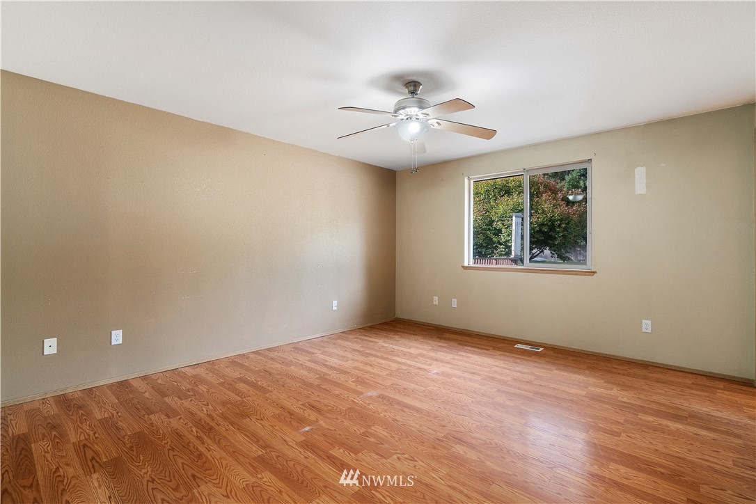 5418 187th Court Southwest Rochester, WA 98579 - Photo 11 of 24 an empty room with wooden floor chandelier fan and windows