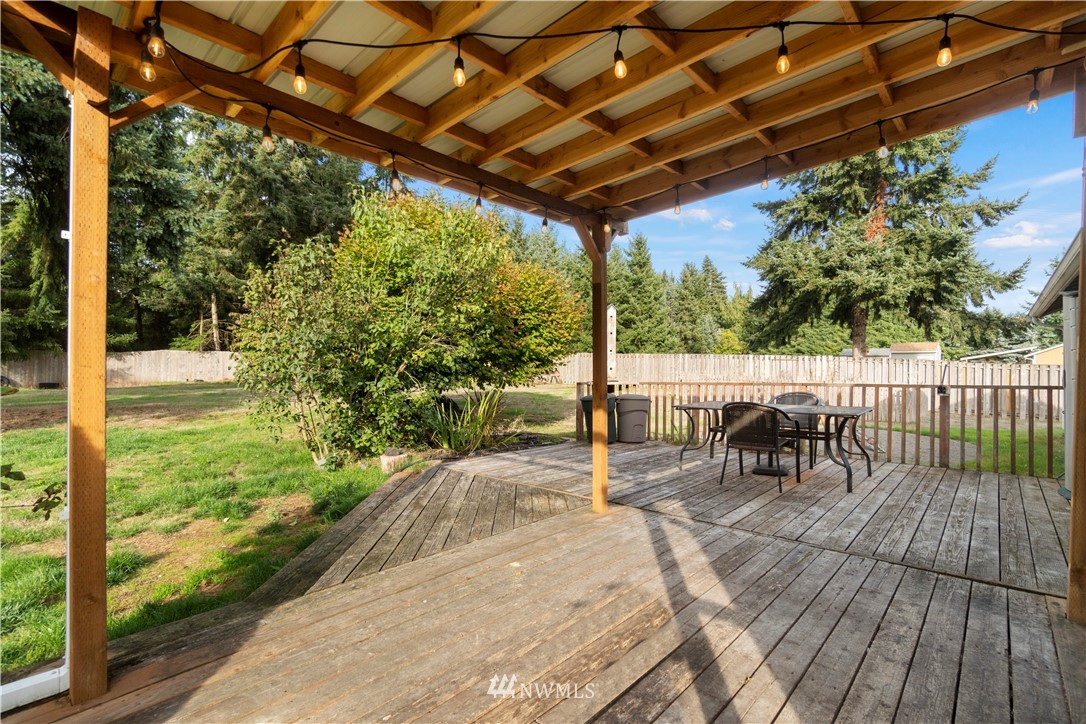 5418 187th Court Southwest Rochester, WA 98579 - Photo 17 of 24 a view of a patio with a table and chairs under an umbrella with a small garden