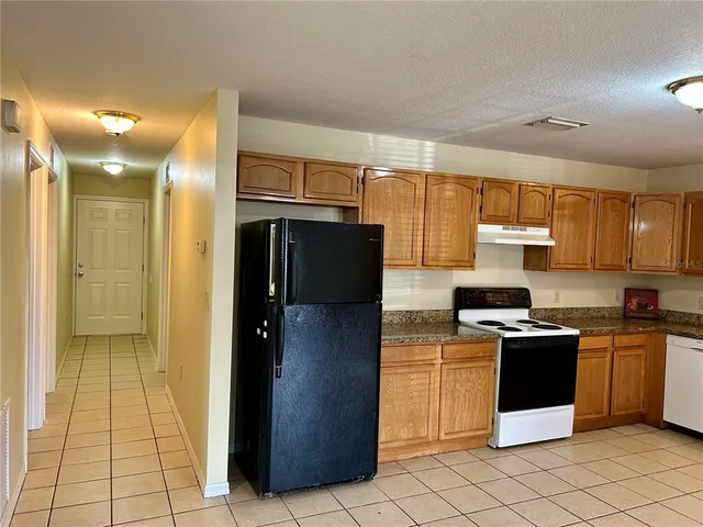 a kitchen with stainless steel appliances granite countertop a refrigerator and a stove top oven
